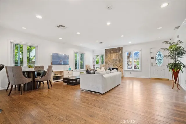 a living room with furniture wooden floor dining table and a large window