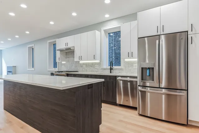 a kitchen with stainless steel appliances granite countertop a refrigerator a sink and a stove