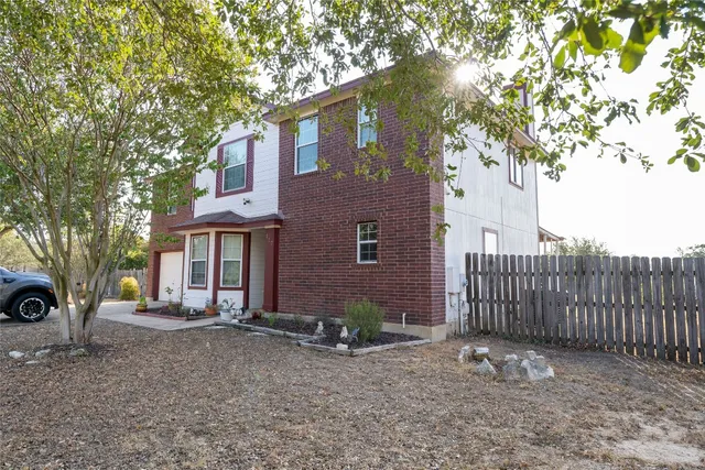 a view of a house with a tree and wooden fence