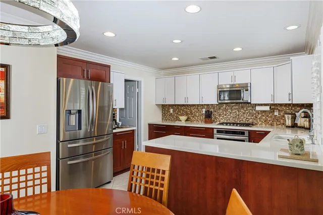 a kitchen with stainless steel appliances granite countertop a refrigerator a stove and a sink with wooden floor