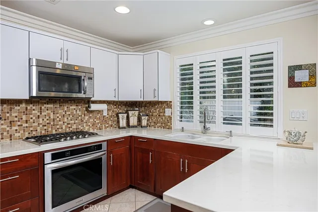 a kitchen with stainless steel appliances granite countertop a sink a stove a microwave and wooden cabinets