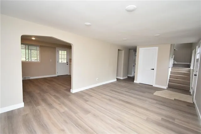 an empty room with wooden floor and entryway