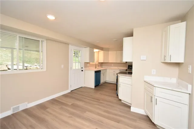 a kitchen with white cabinets and wooden floor
