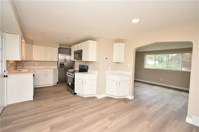 a kitchen with a refrigerator and white cabinets with wooden floor
