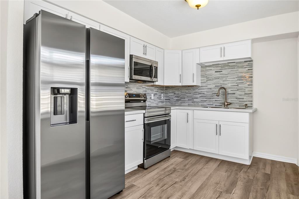 13440 1st Street East Madeira Beach, FL 33708 - Photo 33 of 44 a kitchen with stainless steel appliances granite countertop a refrigerator a sink and white cabinets