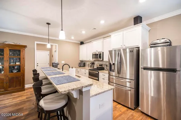 a kitchen with refrigerator a microwave a stove and white cabinets with wooden floor