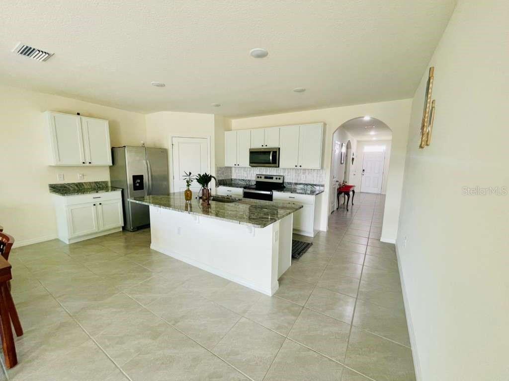8954 Forge Breeze Loop Wesley Chapel, FL 33545 - Photo 28 of 37 a large kitchen with stainless steel appliances a refrigerator a stove top oven a sink dishwasher and white cabinets