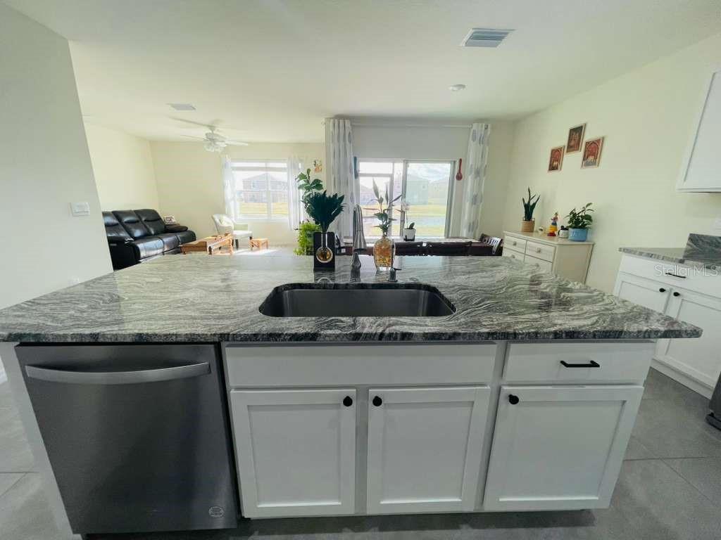 8954 Forge Breeze Loop Wesley Chapel, FL 33545 - Photo 3 of 37 a kitchen with granite countertop a sink a counter space and cabinets