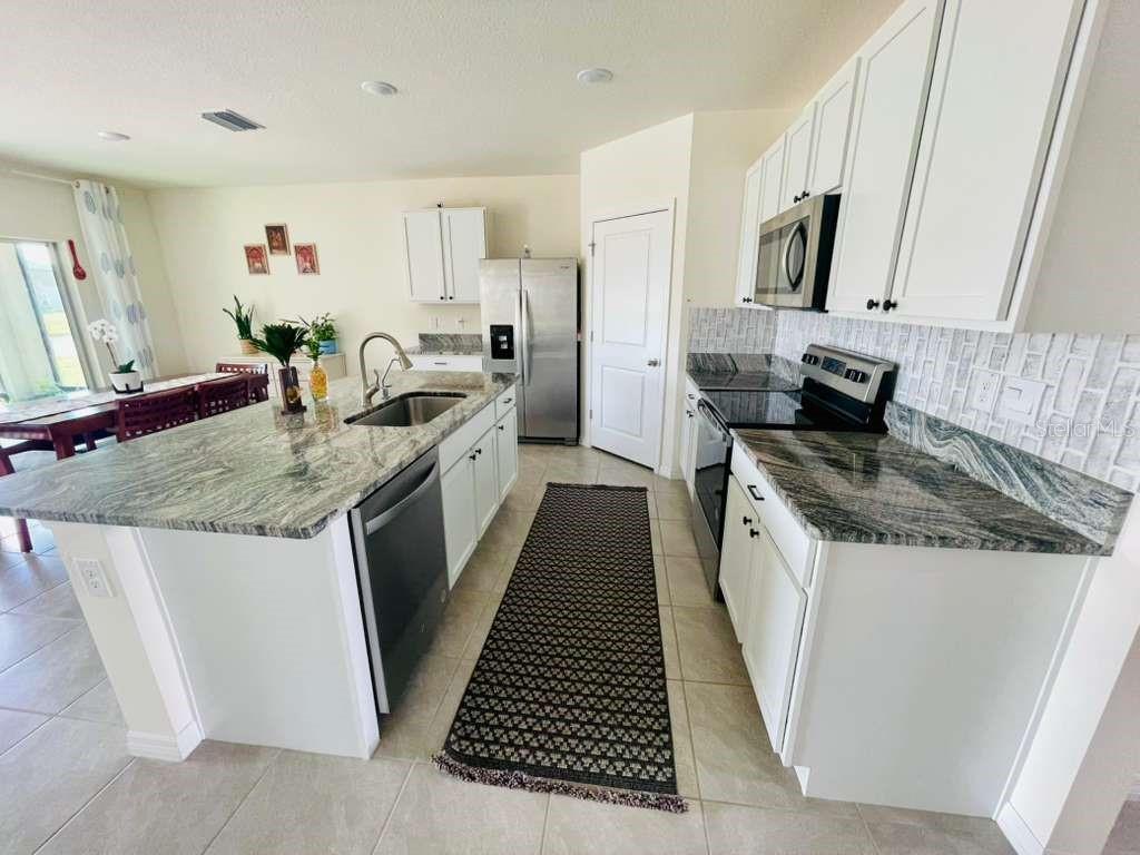 8954 Forge Breeze Loop Wesley Chapel, FL 33545 - Photo 4 of 37 a kitchen with granite countertop a sink stove and cabinets