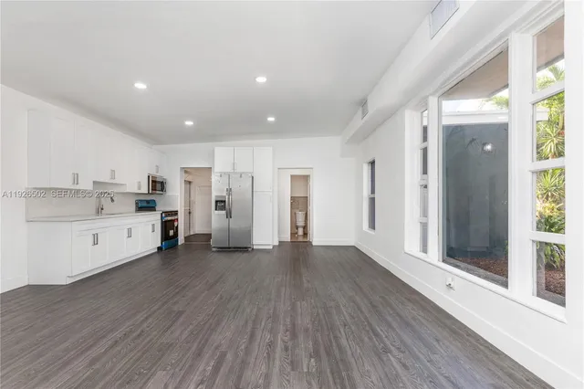 a large white kitchen with stainless steel appliances refrigerator stove and cabinets