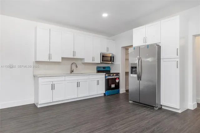 a kitchen with a refrigerator sink and white cabinets