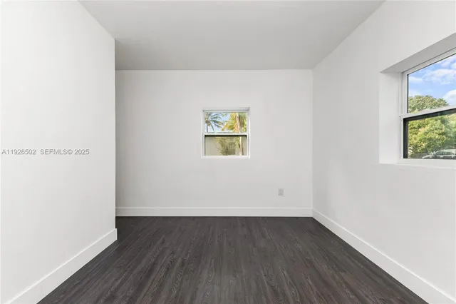 an empty room with wooden floor and window