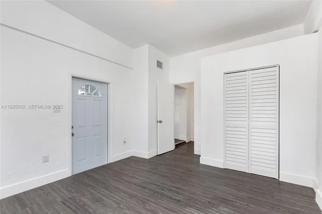 an empty room with wooden floor & closet area