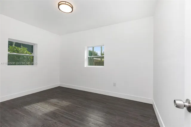 an empty room with wooden floor and window