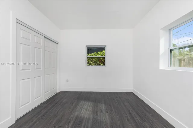 an empty room with wooden floor and window