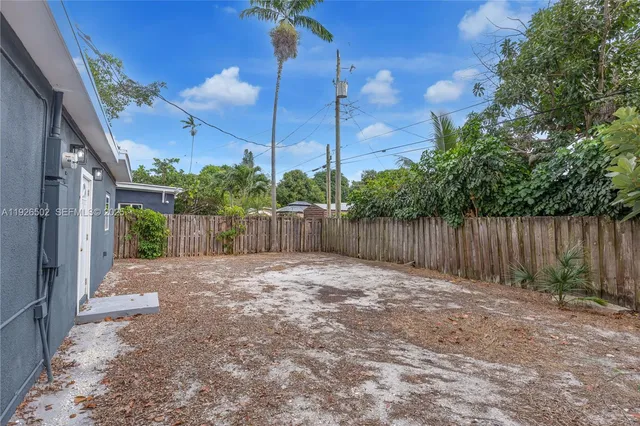 a view of backyard with plants and wooden fence