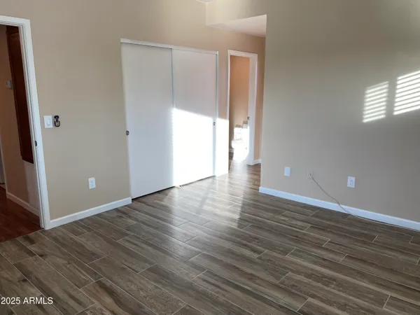 a view of an empty room with wooden floor and a window