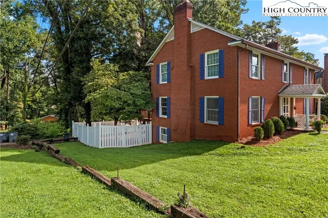 a front view of a house with a yard and tree
