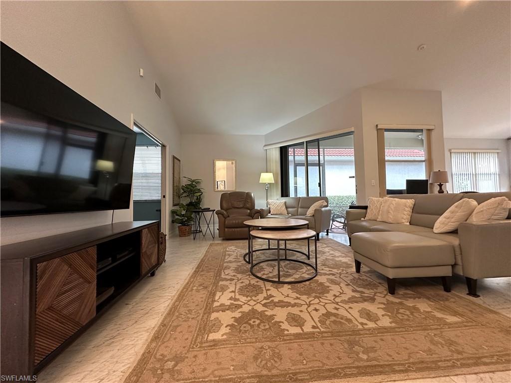 5950 Almaden Drive Naples, FL 34119 - Photo 6 of 22 a living room with furniture a flat screen tv and kitchen view