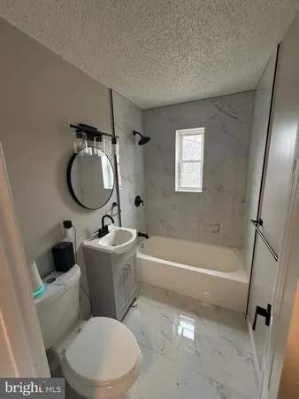 a white toilet sitting next to a bath tub a sink