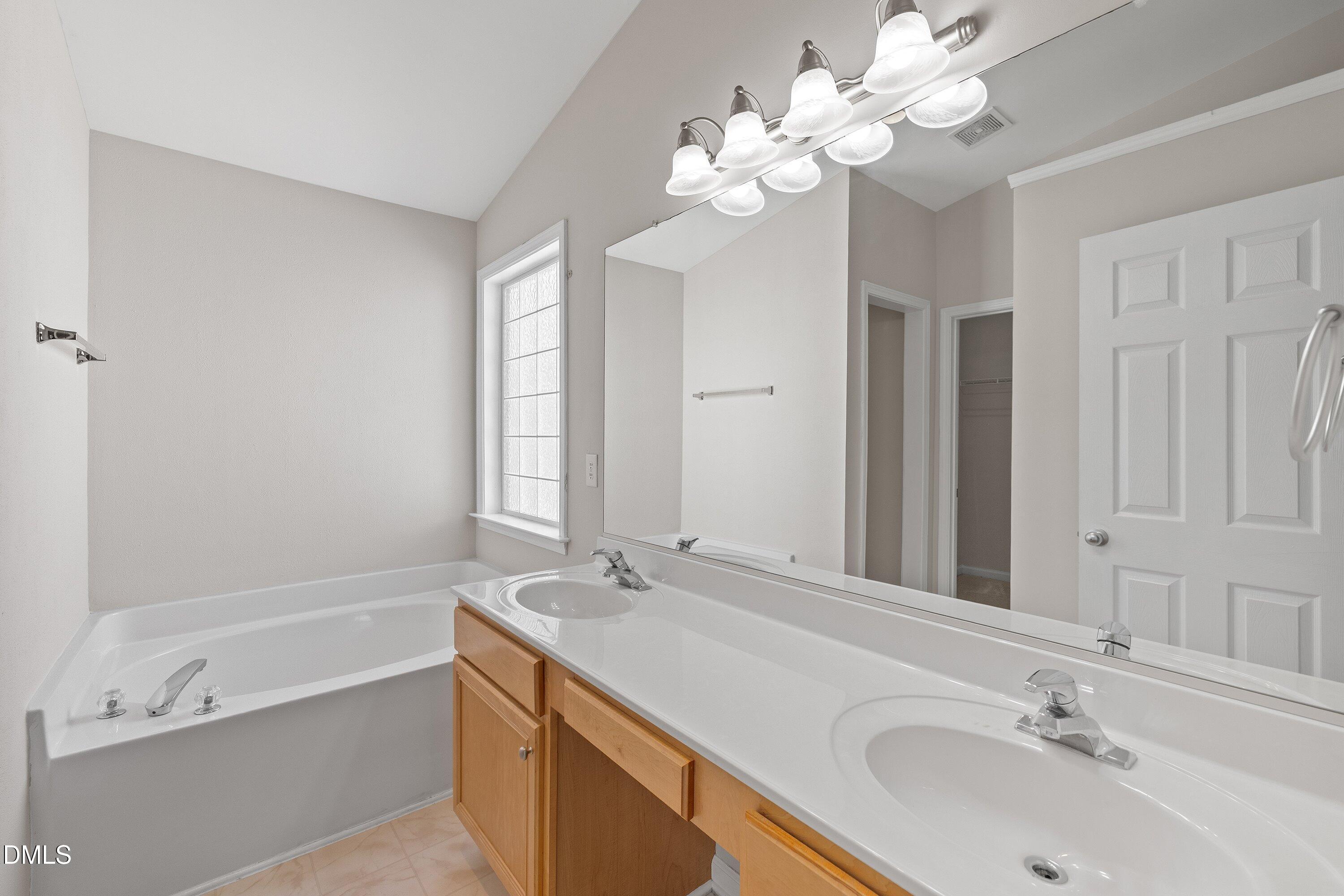 5717 Keowee Way Raleigh, NC 27616 - Photo 20 of 41 a bathroom with a tub a double vanity sink and a mirror