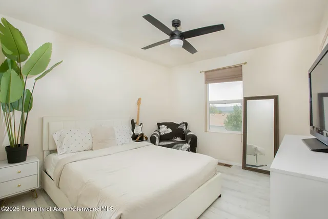 a bedroom with a bed a potted plant and a large window