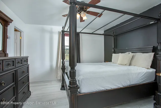 a bedroom with a bed a dresser with flat screen tv