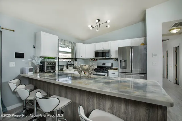 a kitchen with stainless steel appliances granite countertop a table chairs sink refrigerator and microwave