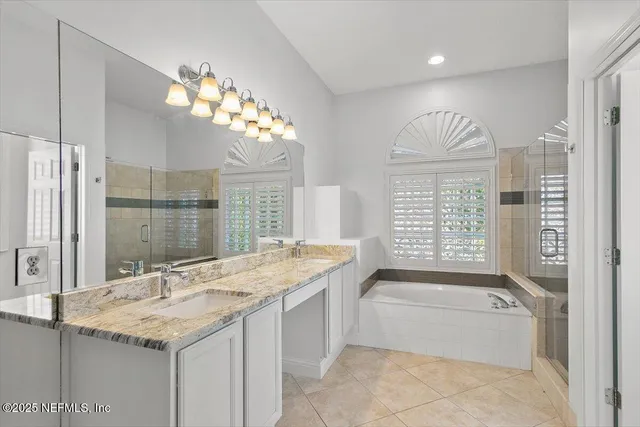 a bathroom with a granite countertop sink a large mirror and a bathtub