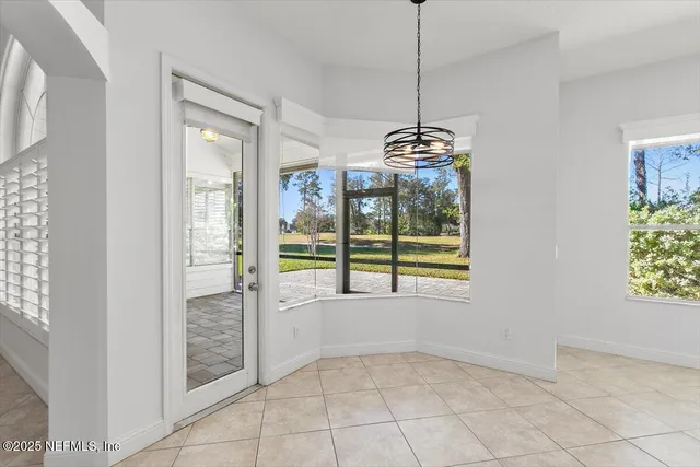 a view of an empty room with window and chandelier