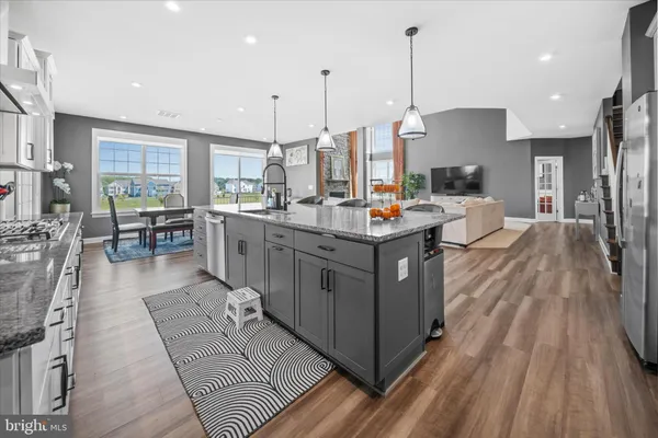 a kitchen with stainless steel appliances a stove a sink a oven a dining table with wooden floor