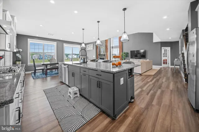 a kitchen with stainless steel appliances a stove a sink a oven a dining table with wooden floor