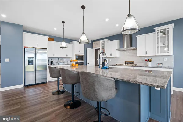 a kitchen with stainless steel appliances granite countertop a table chairs refrigerator and microwave