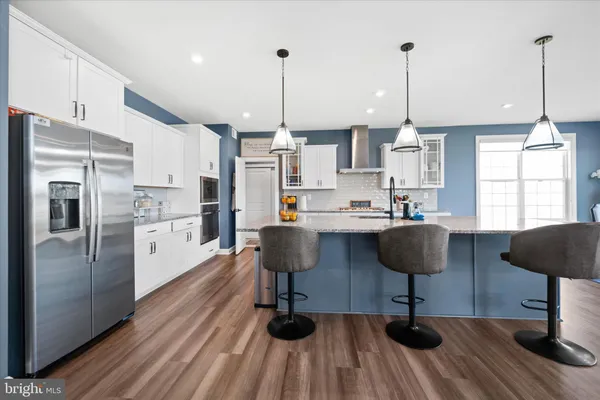 a kitchen with stainless steel appliances a refrigerator a stove a sink dishwasher and a dining table with wooden floor