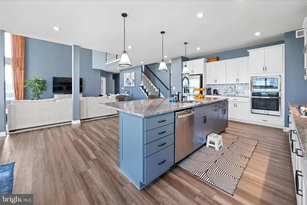 a view of a kitchen with kitchen island a counter top space a sink and wooden floor