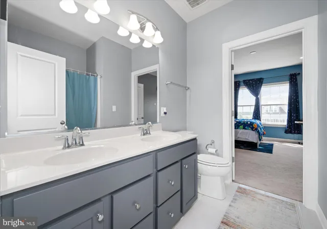 a en suite bathroom with a double vanity sink a toilet and a mirror