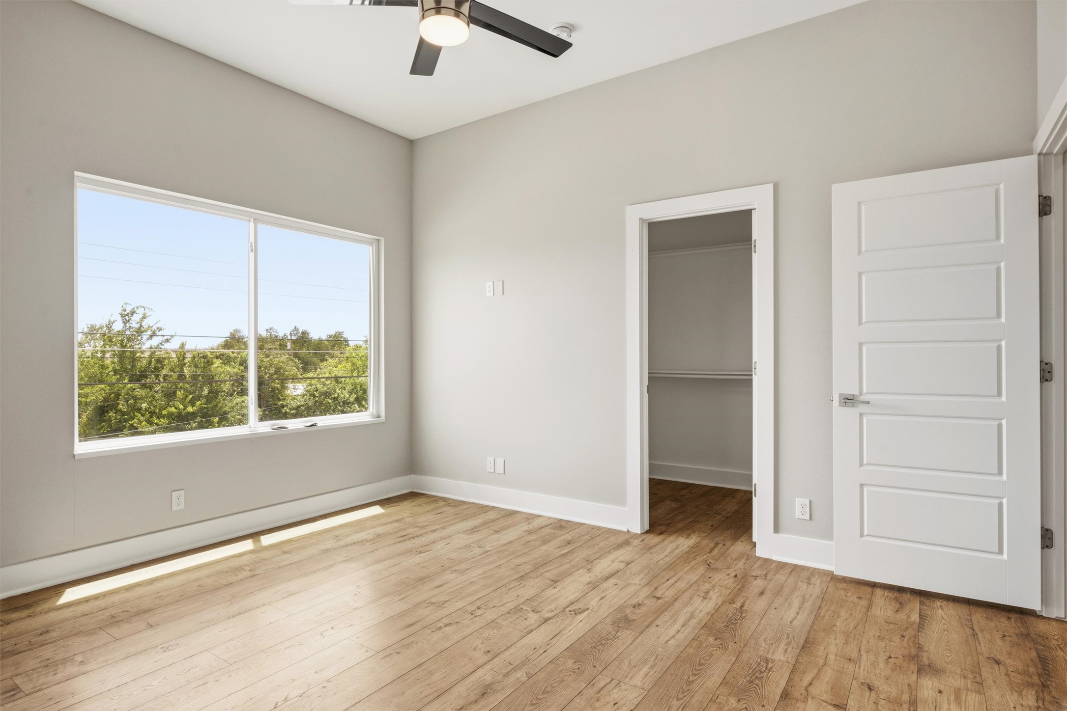 1210 Stobaugh Street, Unit B Austin, TX 78757 - Photo 13 of 40 A tranquil bedroom featuring wood flooring and a large window overlooking lush greenery.