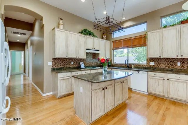 a kitchen with kitchen island granite countertop a sink appliances cabinets and a counter top space
