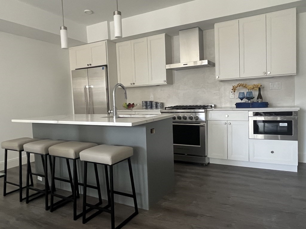 765 East 3rd Street, Unit 202 Boston, MA 02127 - Photo 8 of 9 a kitchen with stainless steel appliances granite countertop a stove a sink refrigerator and white cabinets