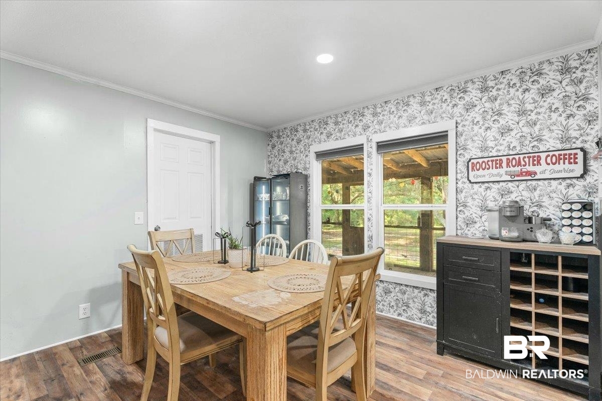 21011 River Road Robertsdale, AL 36567 - Photo 10 of 29 Dining area featuring wood-finish flooring, two large windows, white crown molding, and a built-in beverage cabinet with shelving