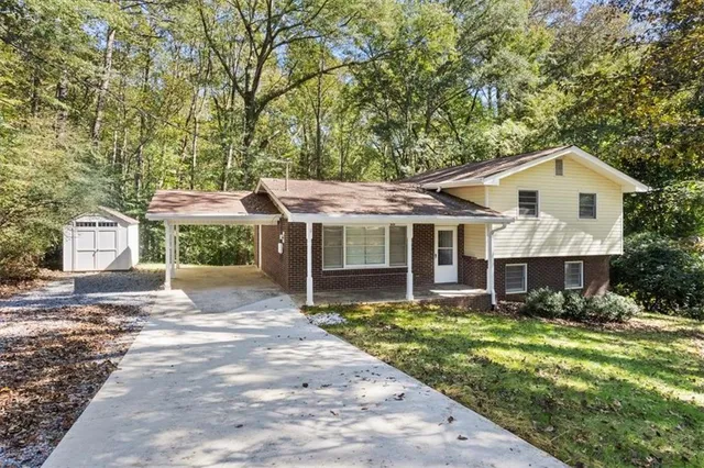 a view of a house with a yard and large trees