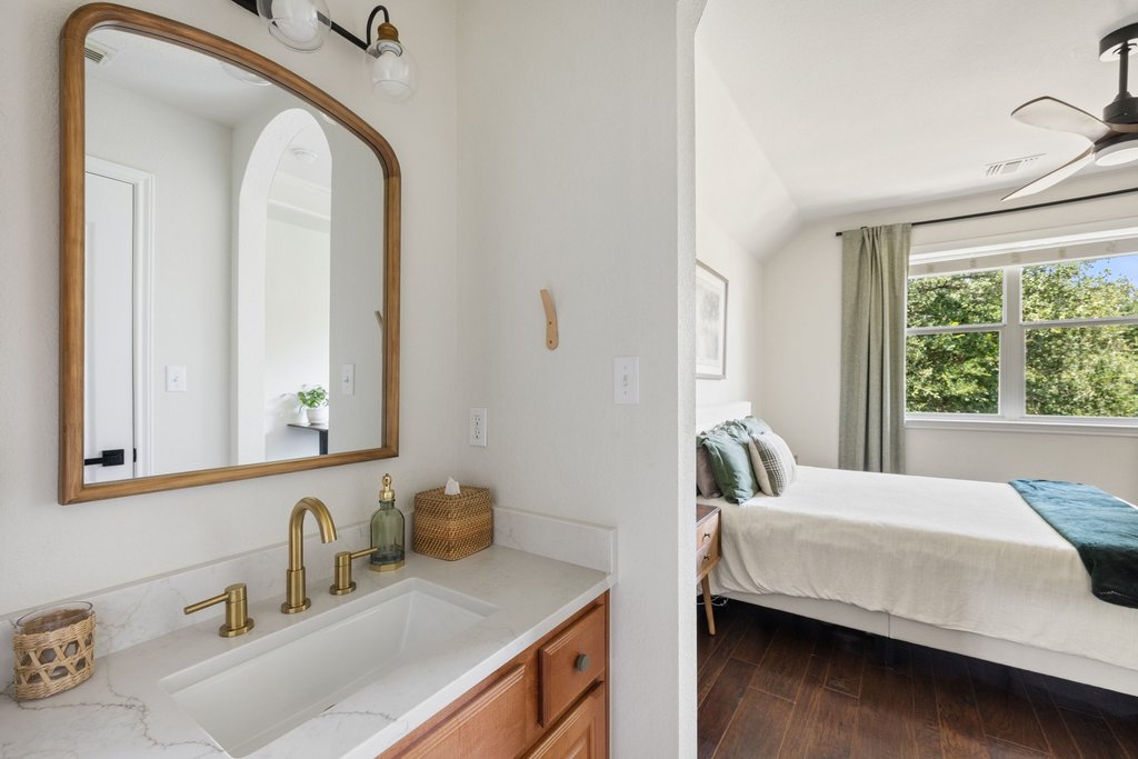 6704 Kiev Cove Austin, TX 78739 - Photo 25 of 37 A well-appointed bathroom vanity with a gleaming brass faucet offers seamless transition to a cozy, naturally lit sleeping area.