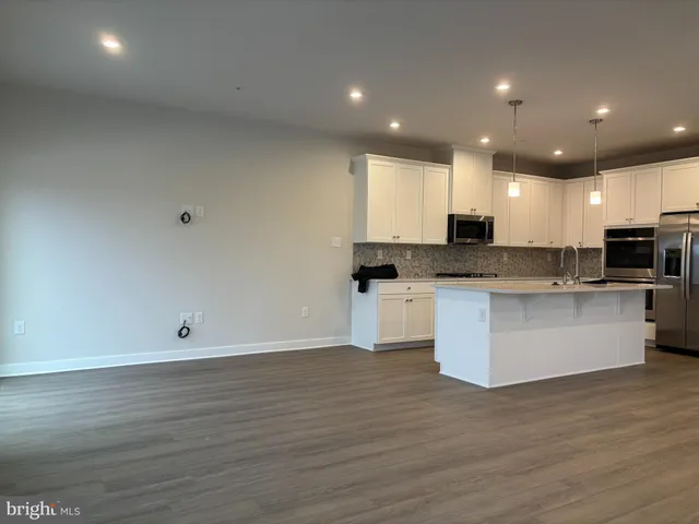 a large kitchen with stainless steel appliances a large counter top a stove a sink and a refrigerator