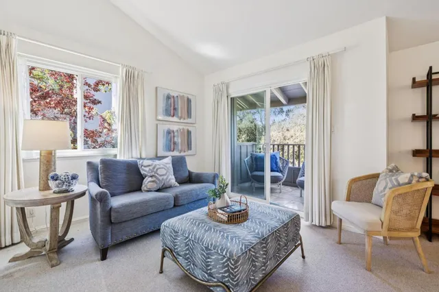 a living room with furniture a rug a lamp and a large window
