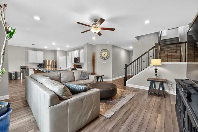 a living room with furniture kitchen view and a wooden floor