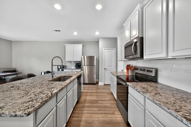 a kitchen with stainless steel appliances granite countertop a sink stove and refrigerator