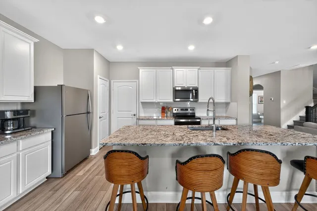 a kitchen with stainless steel appliances granite countertop a stove a refrigerator a sink a dining table and chairs