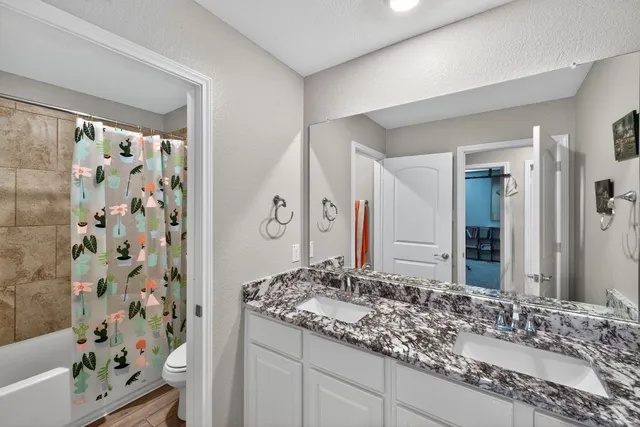 a bathroom with a granite countertop sink a mirror a vanity and a shower