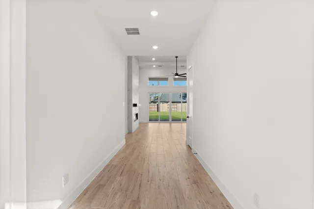 a view of a hallway with wooden floor and a refrigerator