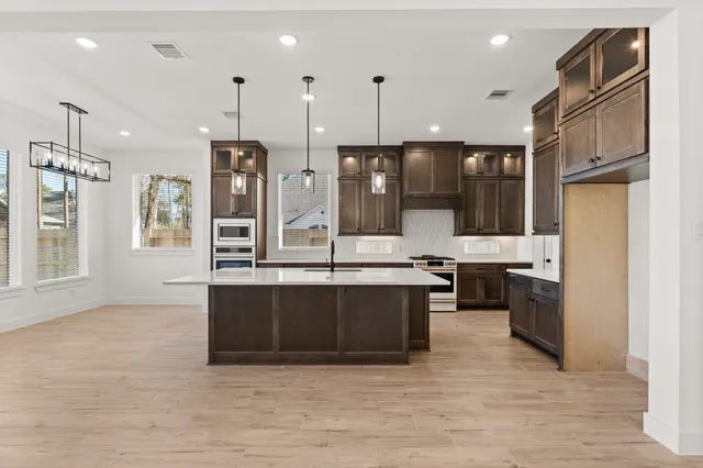a view of kitchen with stainless steel appliances granite countertop a stove a sink a refrigerator and a center island